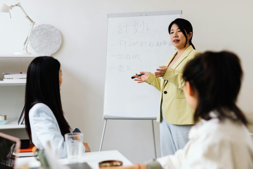 Business workshop presenter leading a team meeting and explaining strategy on a whiteboard.