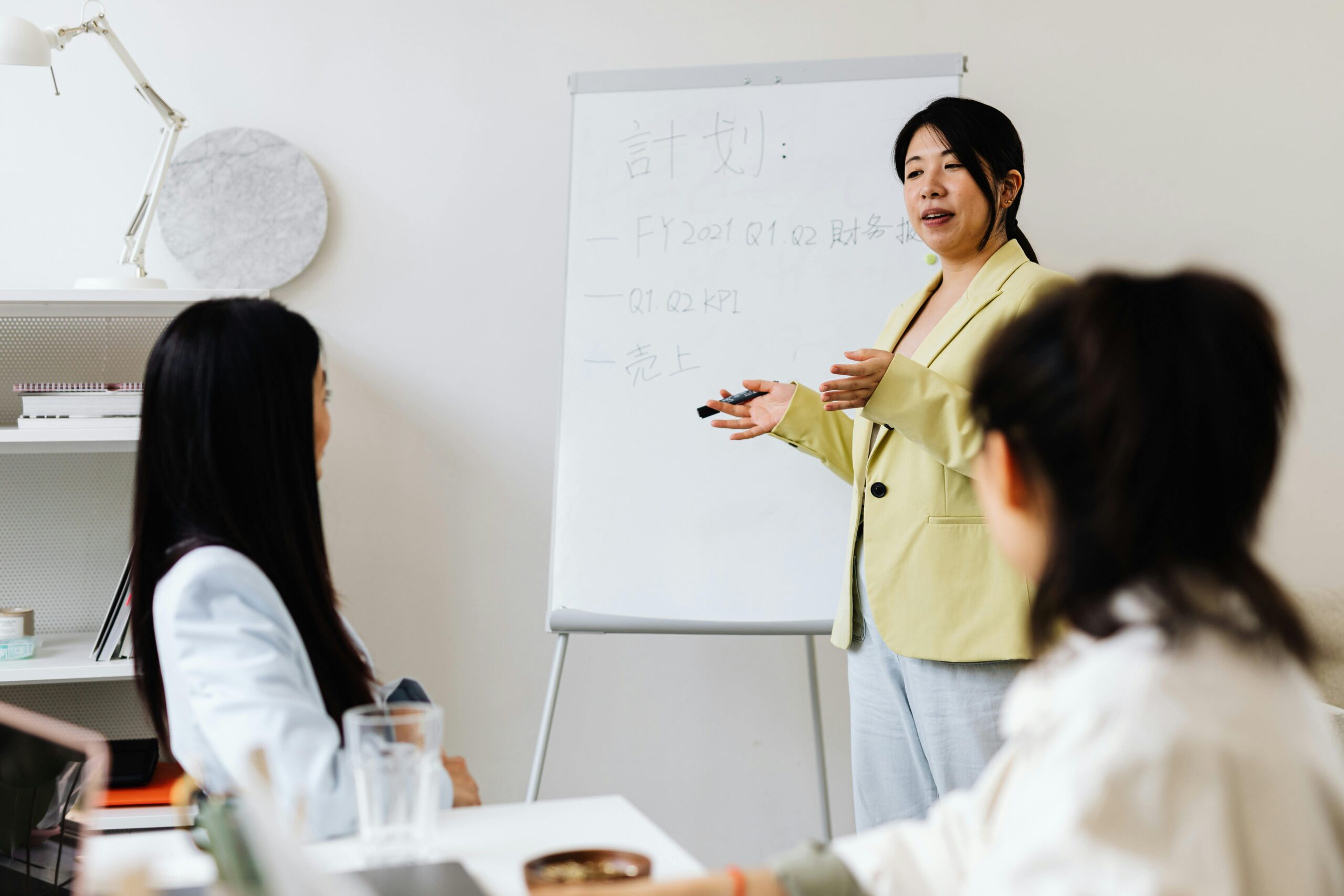 Business workshop presenter leading a team meeting and explaining strategy on a whiteboard.