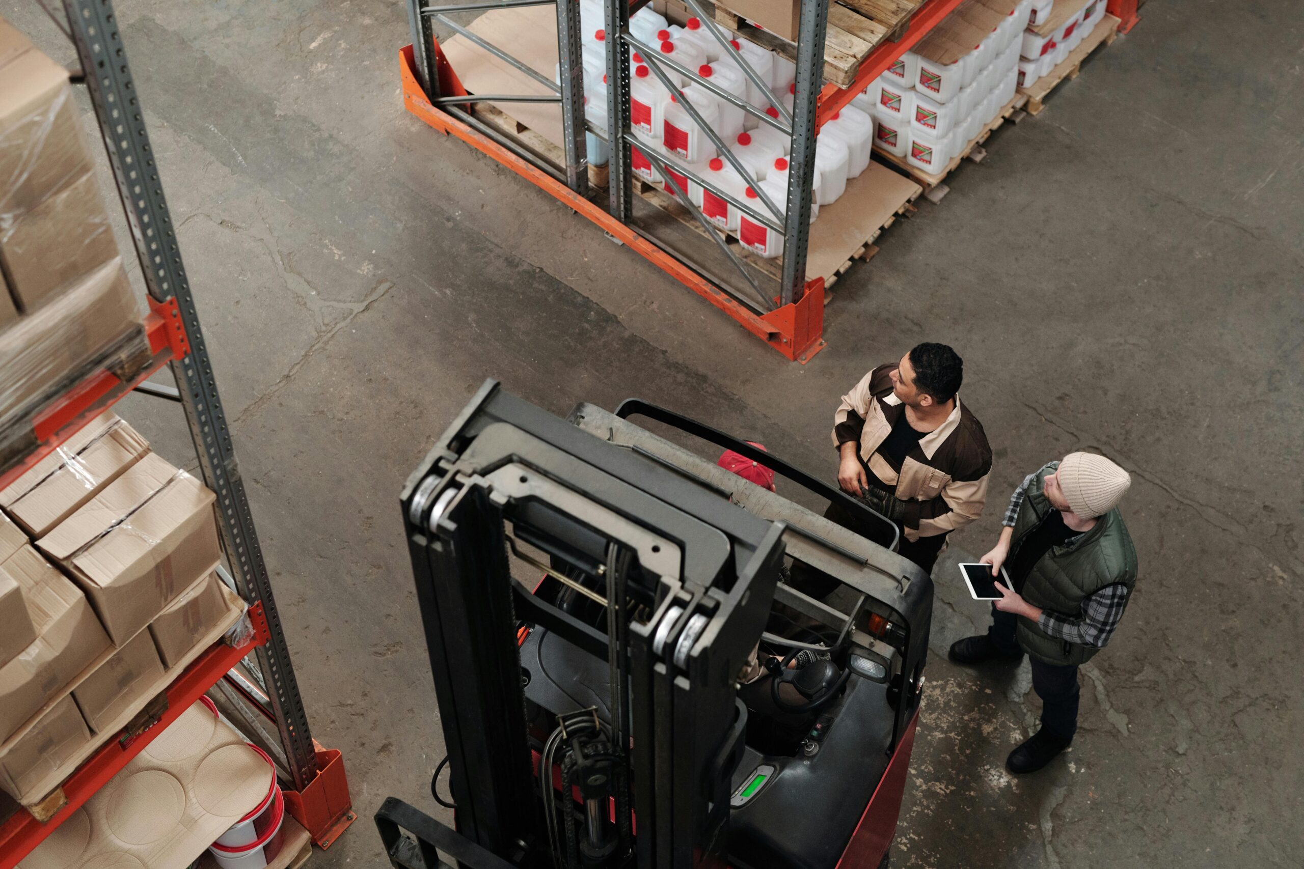 Warehouse workers using a forklift and tablet to manage inventory and distribution operations.