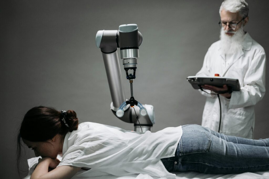 Healthcare professional using robotic medical technology to treat a patient lying on an examination table.