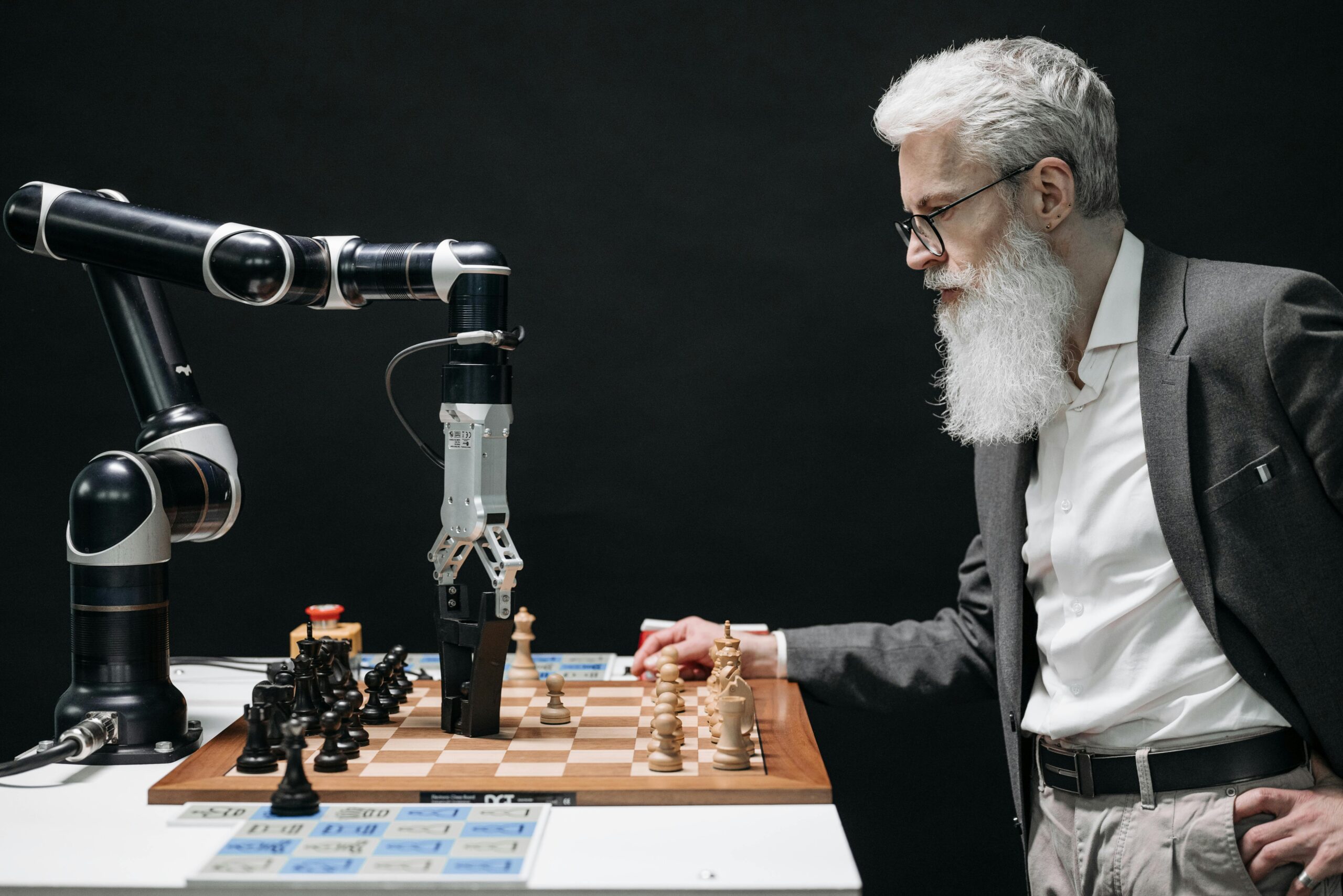 Businessman playing chess against a robotic arm, illustrating human versus AI strategy and automation.