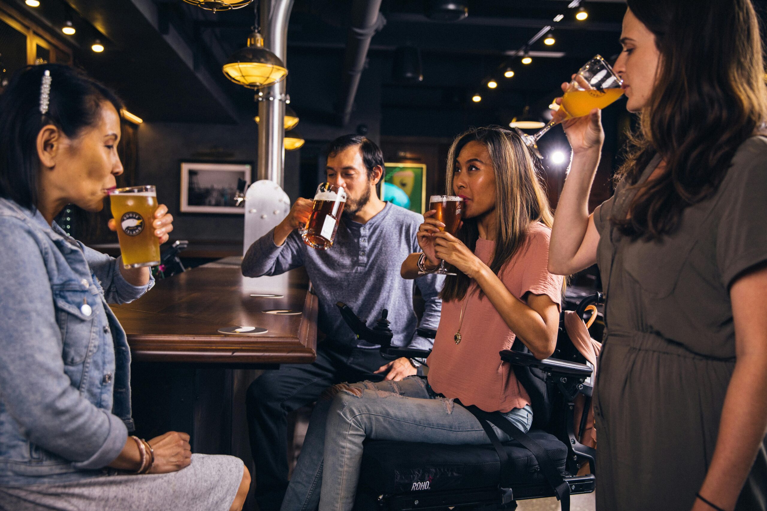Group of friends socialising at a bar, drinking craft beer and enjoying a night out together.